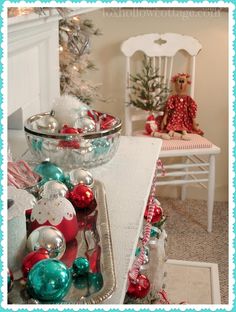 a christmas tree with ornaments in a bowl on the table next to a white chair