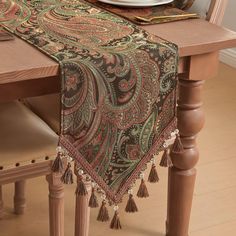 a table with a place setting on it and a plate in the middle, along with a napkin that has tassels