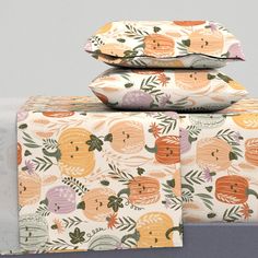 three pillows stacked on top of each other in front of a white wall with an orange and green pattern