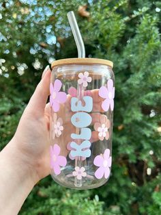 a hand holding a pink and blue flowered tumbler with the word love on it