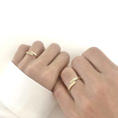 two hands holding each other with gold rings on their fingers and one is wearing a white shirt