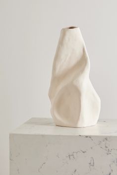 a white vase sitting on top of a marble block