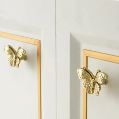 two white cabinets with gold handles and knobs on the doors, one has a butterfly shaped door handle