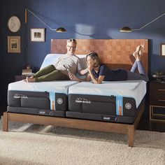 two people laying on top of a mattress in a bedroom