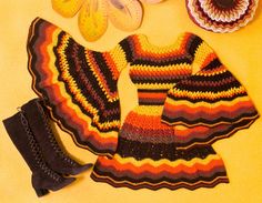 crocheted clothing and accessories are laid out on a yellow surface with flower petals