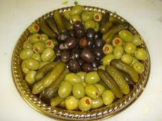 a bowl filled with olives and pickles on top of a white countertop