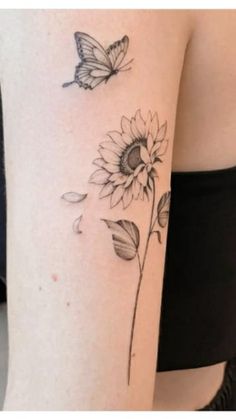 a sunflower and butterfly tattoo on the right side of the thigh, it is black and white