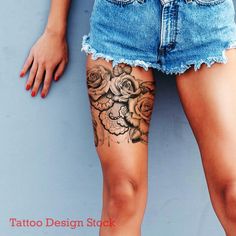 a woman's legs with tattoos and flowers on her leg, next to a blue wall