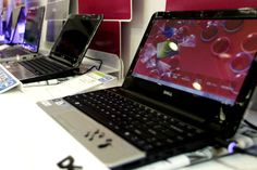 three laptops sitting on top of a table with red and white walls behind them