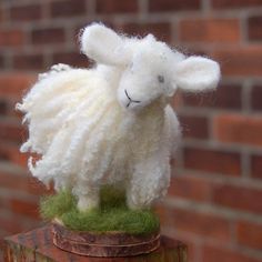 a white sheep is sitting on top of a piece of wood