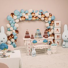 a baby's first birthday party decorated with balloons and bunnies, including an arch