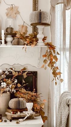 a white fireplace mantel topped with lots of fall leaves and other decorating items