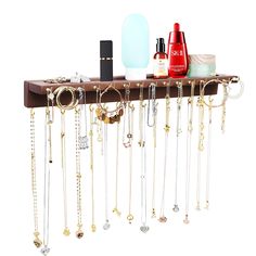 a wooden shelf with various jewelry hanging from it's sides and two bottles on top