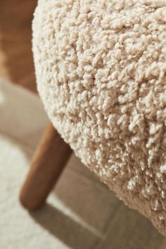 the back end of a sheep's wool covered chair with a wooden arm rest