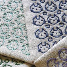 three different colored designs on fabric with one blue and the other green, sitting next to each other