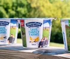 three yogurt cups sitting on top of a wooden table next to each other