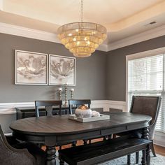 a dinning room table with chairs and a bench in front of two pictures on the wall