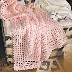 a teddy bear laying on top of a bed covered in pink crocheted blankets