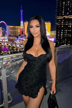 a woman in a black dress standing on a balcony with the las vegas skyline in the background