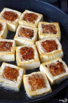 square pieces of bread with sauce cooking in a skillet on the stove, ready to be cooked