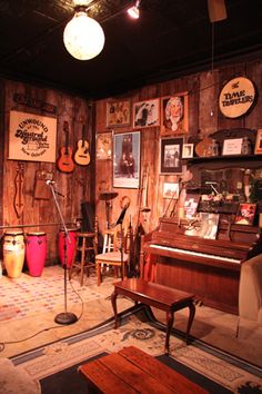 a room filled with musical instruments and pictures on the wooden wall behind it is a piano