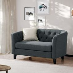 a living room scene with focus on the couch and chair in the foreground, framed pictures on the wall