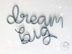 the words dream love are made out of string and beads on a white background with snow flakes