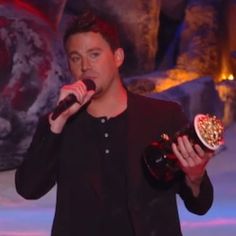 the man is holding two bottles of wine in his hands and singing into a microphone