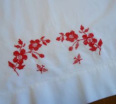 red flowers are embroidered on white linens