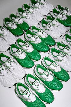 green and white tennis shoes are lined up on the floor in rows, with one being folded down