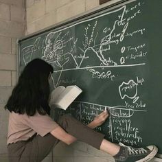 a woman writing on a blackboard with chalk