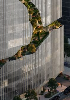 an aerial view of a curved building with trees on the side and cars driving down the street