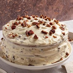 a cake with white frosting and pecans on top