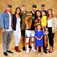 a group of people standing next to each other in front of a wall holding a trophy