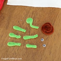 a wooden table topped with lots of green items and plastic scissors on top of it