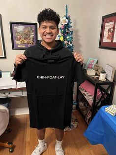 a young man holding up a black shirt with the word chh - potatolay on it