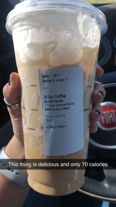 a person holding up a cup of iced coffee in their hand with the label on it