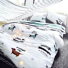 a bed covered in white sheets with dogs on them and lights strung from the covers