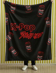 a person holding up a black k - pop banner