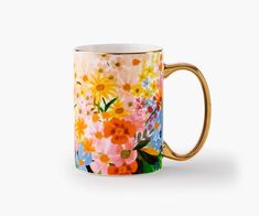 a coffee mug with colorful flowers painted on the outside and gold trimming around it