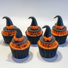 six cupcakes with black and orange decorations are arranged in the shape of witches hats