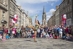 a woman is dancing in the middle of a street while people watch from behind her