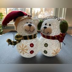 two snowmen made out of glass sitting on top of a table