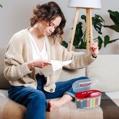 a woman is sitting on the couch with some craft supplies in her hand and she is looking at something