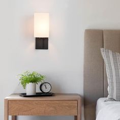 a nightstand with a clock on it next to a bed