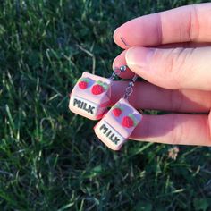 a hand holding two pink dices that say milk and strawberries on the side