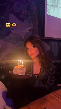 a woman sitting in front of a cake with lit candles