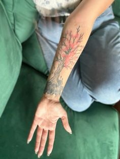 a woman with a tattoo on her arm is sitting on a couch and reaching out