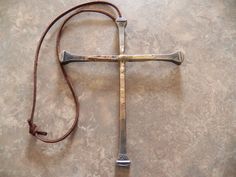 an old metal cross laying on top of a stone floor next to a brown cord