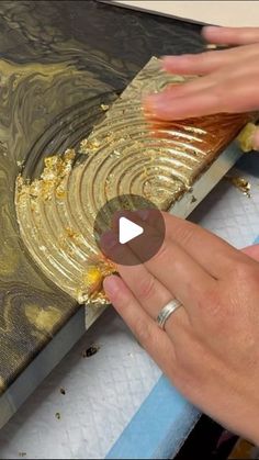 a woman is peeling gold leaf from a piece of art